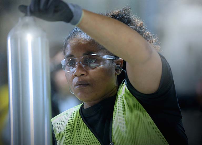 Woman holding up cylinders in manufacturing facility